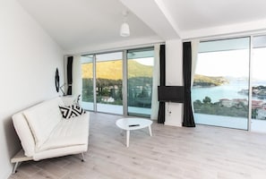 Enjoy a serene coastal view from the comfort of this stylish living room, featuring a sofa, side table, and flat-screen TV.