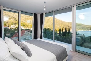 Enjoy a serene retreat with expansive views of the surrounding mountains and water from this stylish bedroom.