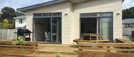 A modern house with a patio area featuring wooden benches and a grill.