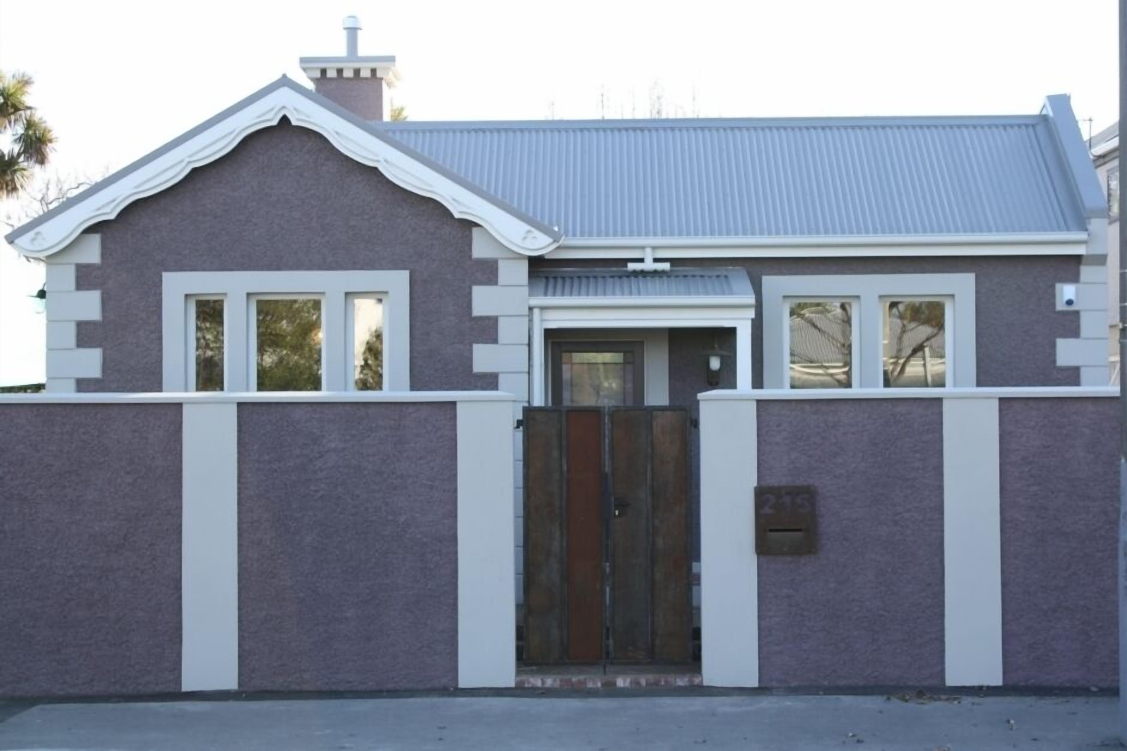 A two-story building with a grey roof, white trim, and a metal gate.