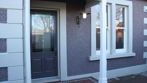 Une entrée de maison avec une porte sombre, des moulures blanches et une petite fenêtre avec un luminaire.