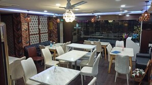 Un restaurant doté de nombreuses tables et chaises, de ventilateurs de plafond et d’un éclairage décoratif.