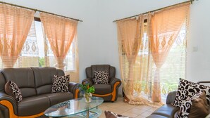 A living room with two sofas, a glass coffee table, and patterned cushions. - Chez Odet (Mahé Island)