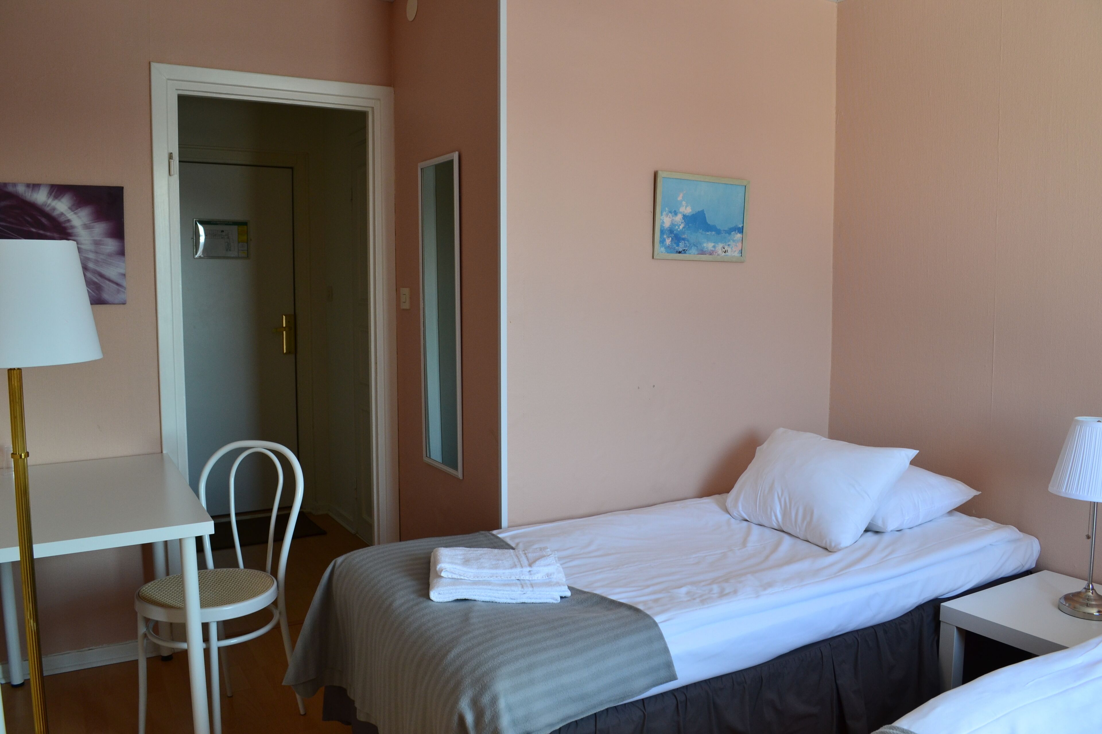 Una habitación de hotel con cama, una silla, un escritorio y una lámpara.