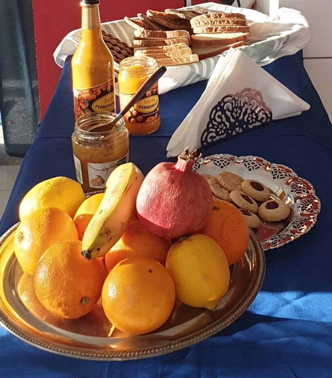 A table with a variety of food items including oranges, a pomegranate, cookies, and bread.