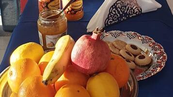 A table with a variety of food items including oranges, a pomegranate, cookies, and bread.