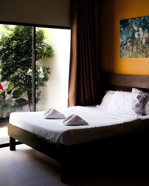 Ein ordentlich bezogenes Bett mit weißen Leinentüchern und Handtüchern, ein großes Fenster mit Blick auf Grünflächen und ein Bild an der Wand.