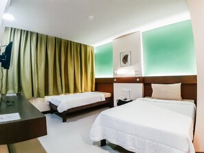 A hotel room with two beds, a desk, and a green wall. - Cres Ebo Mansion Hotel and Bistro (Tagbilaran)