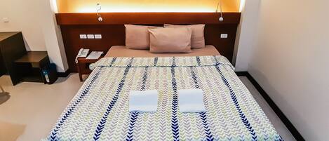 Una habitación de hotel con una cama, una mesita de noche, un cuadro en la pared y una escalera.