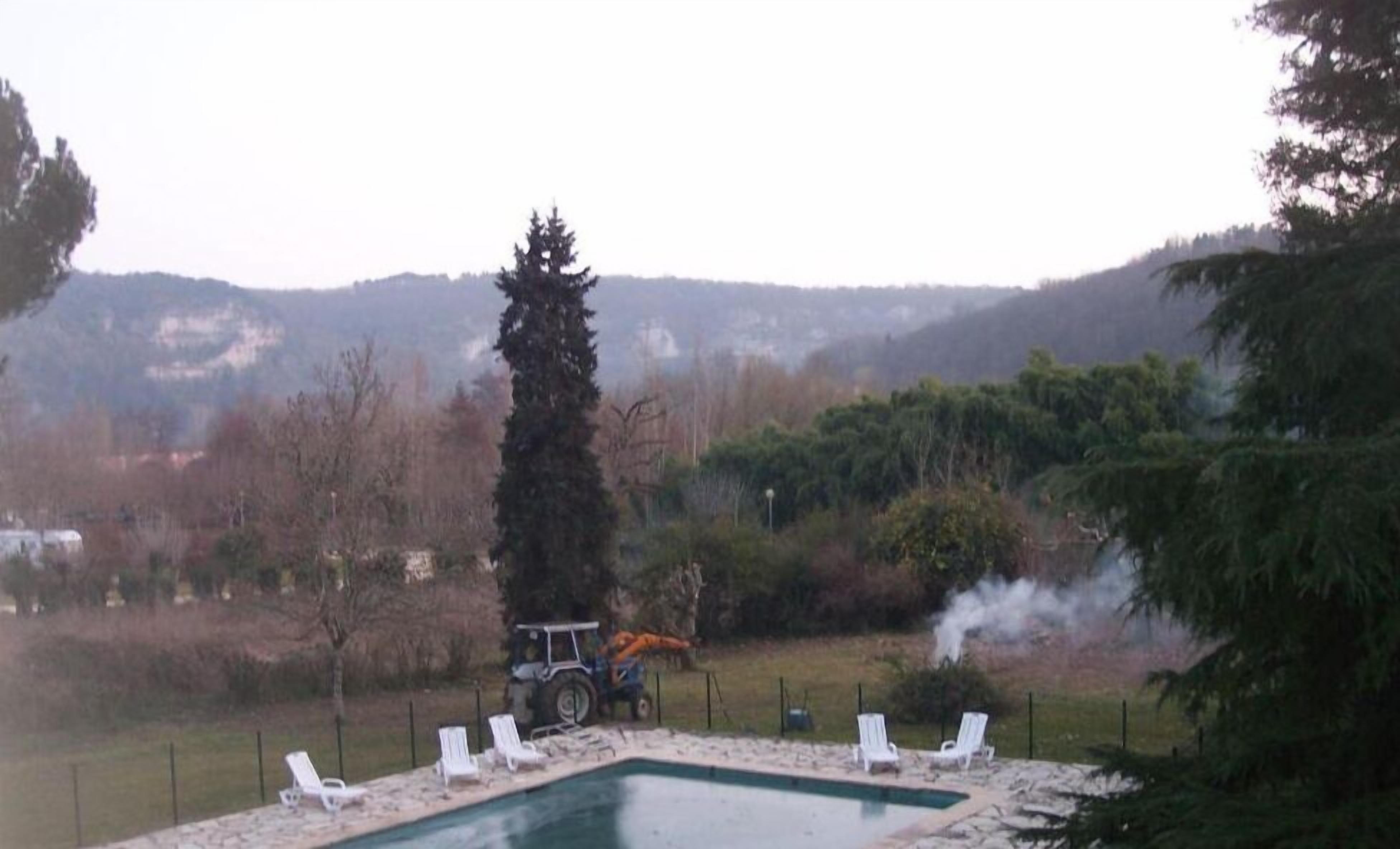 A swimming pool with lounge chairs and a vehicle in the background.