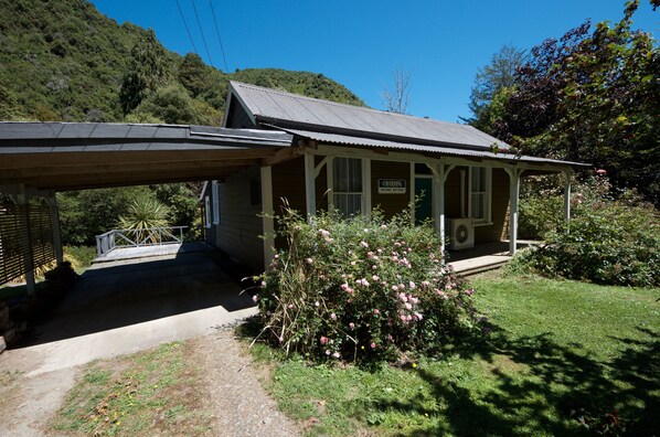 A small, single-story building with a porch and a sign that reads "Caring Military Cottage." - Charming older style cottage . (West Coast)
