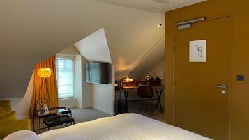 Una habitación de hotel con cama, escritorio, silla, lámpara y puerta.