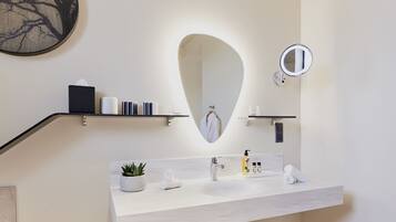 Une salle de bain moderne avec un meuble-lavabo, un grand miroir, un porte-serviettes et une étagère contenant des articles de toilette.