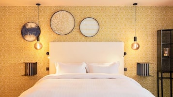 Una habitación de hotel con una cama grande, dos lámparas de pared y tres obras de arte colgadas.