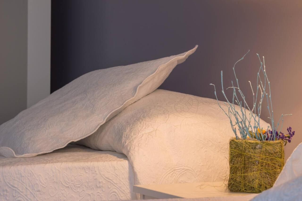 A bed with white pillows and a woven basket containing dried plants.