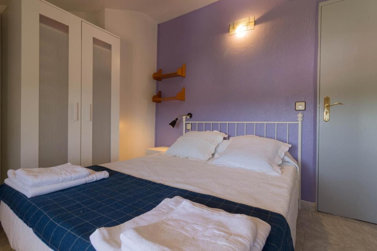 A bedroom with a bed, two wardrobes, a nightstand, and a wall-mounted lamp.