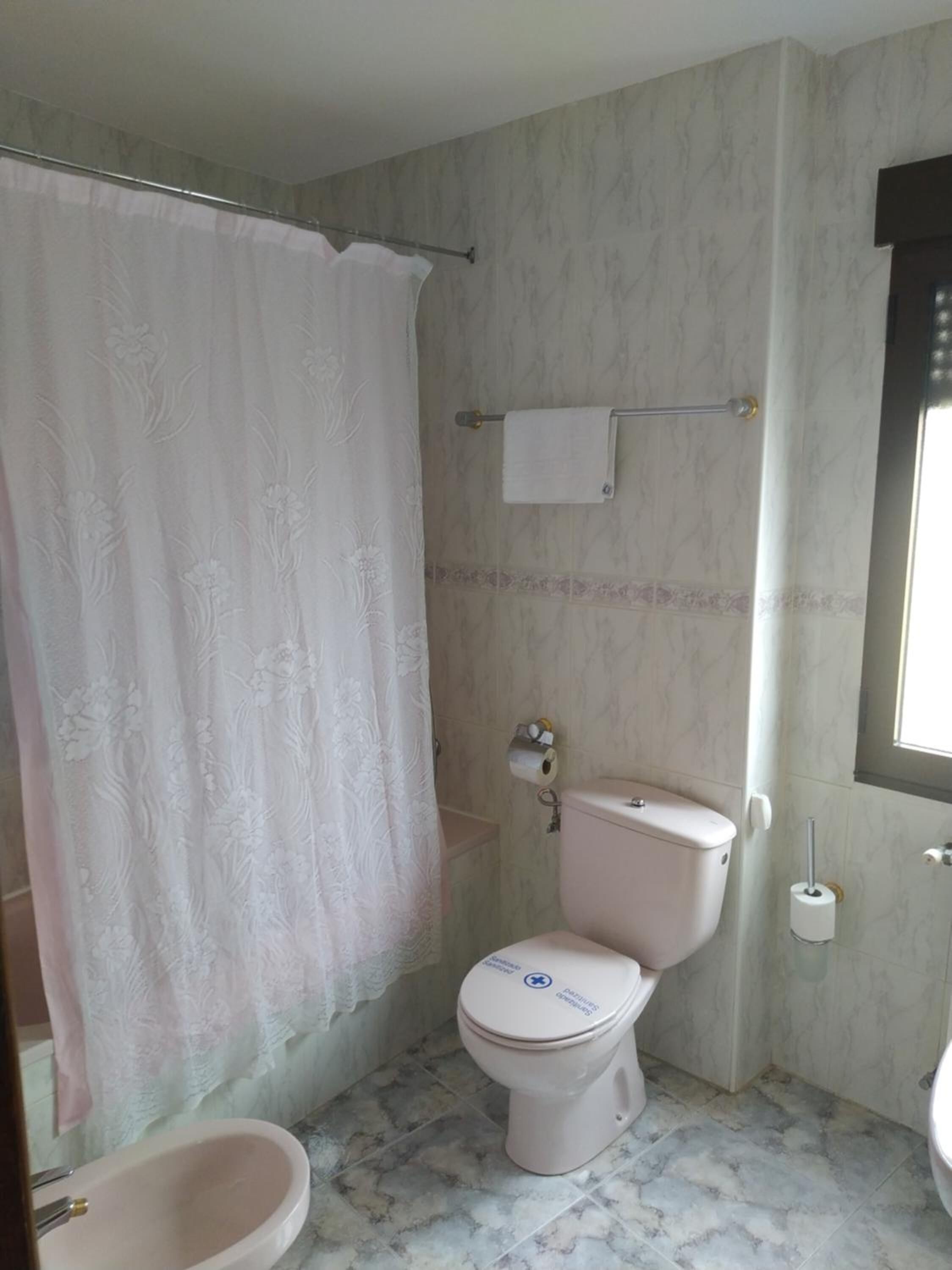 Un baño con inodoro, lavabo y cortina de ducha.