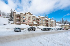 A multi-story hotel with balconies and a parking lot filled with cars.