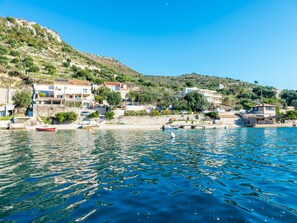 Un pueblo costero con edificaciones a lo largo de la orilla, un muelle y un bote.