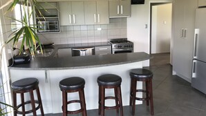 Una cocina moderna con armarios grises, estufa de acero inoxidable y una barra con taburetes.