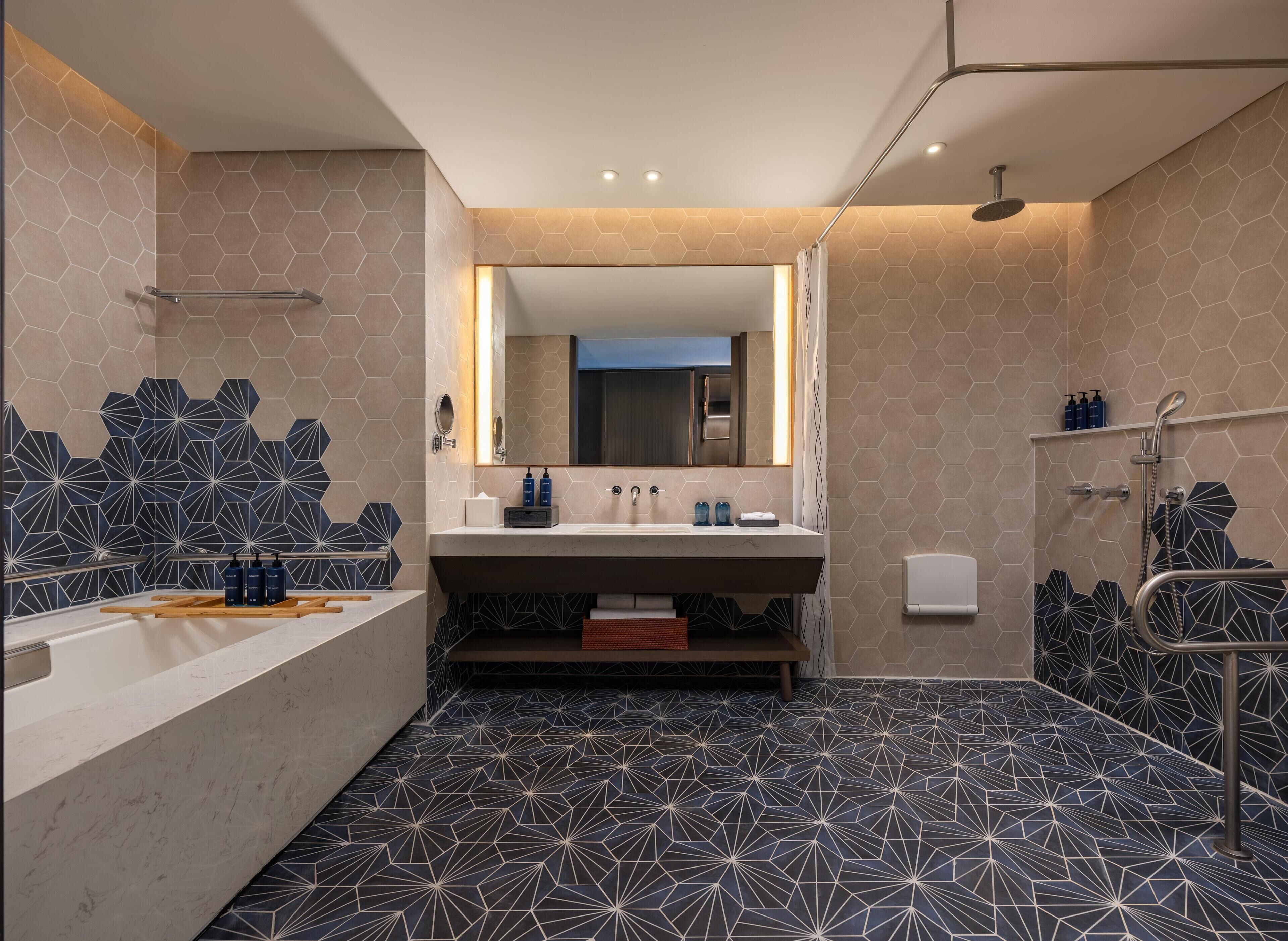 Ein modernes Badezimmer mit großem Spiegel, Badewanne, Dusche und Waschtisch.