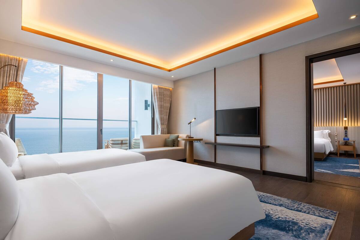 Ein modernes Hotelzimmer mit einem großen Bett, einem Fernseher und Meerblick.