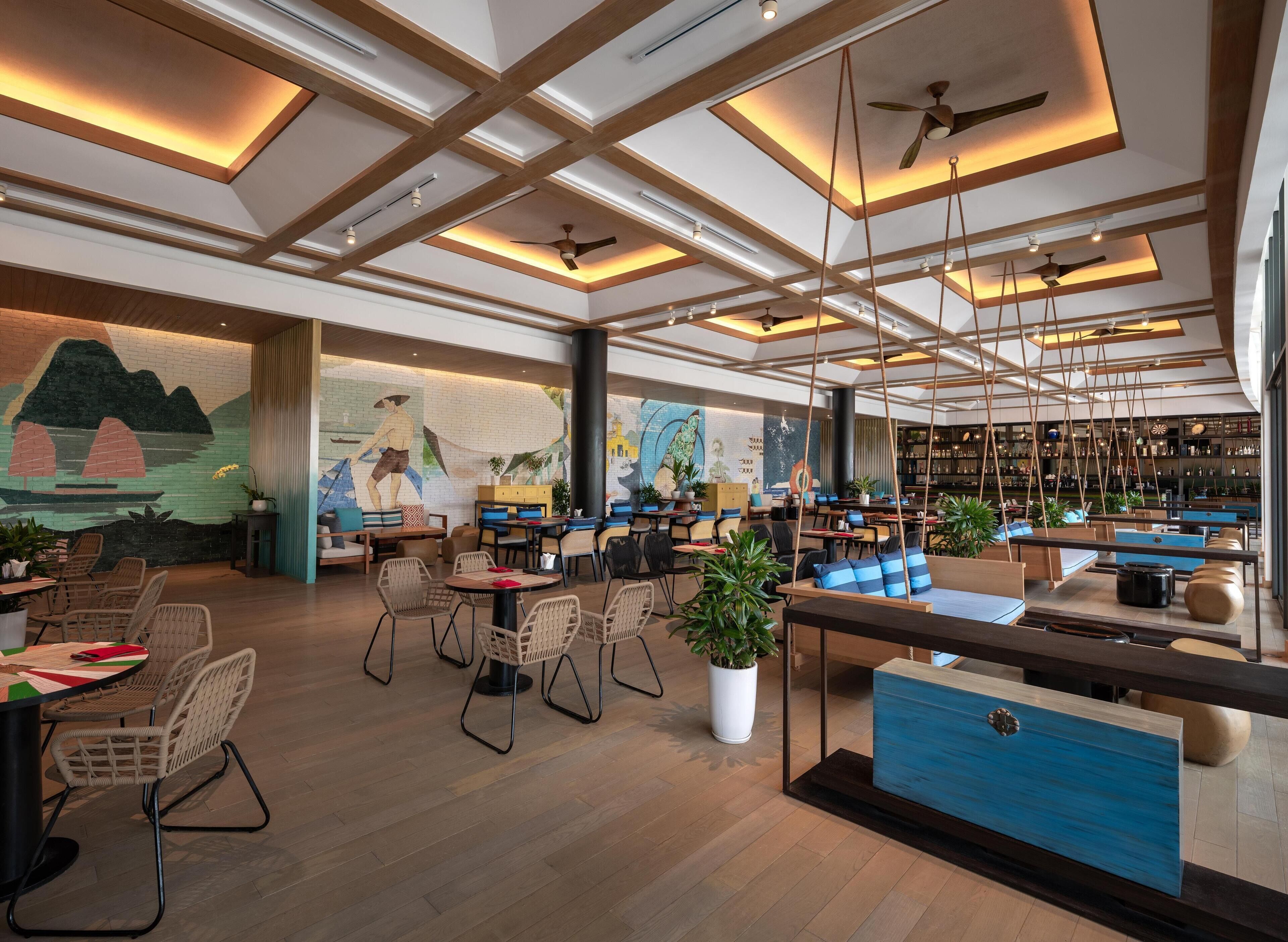 A modern restaurant with high ceilings, exposed beams, and a variety of seating options including tables and booths.