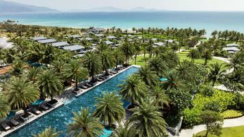 Un resort con una piscina larga rodeada de palmeras y vista al océano.