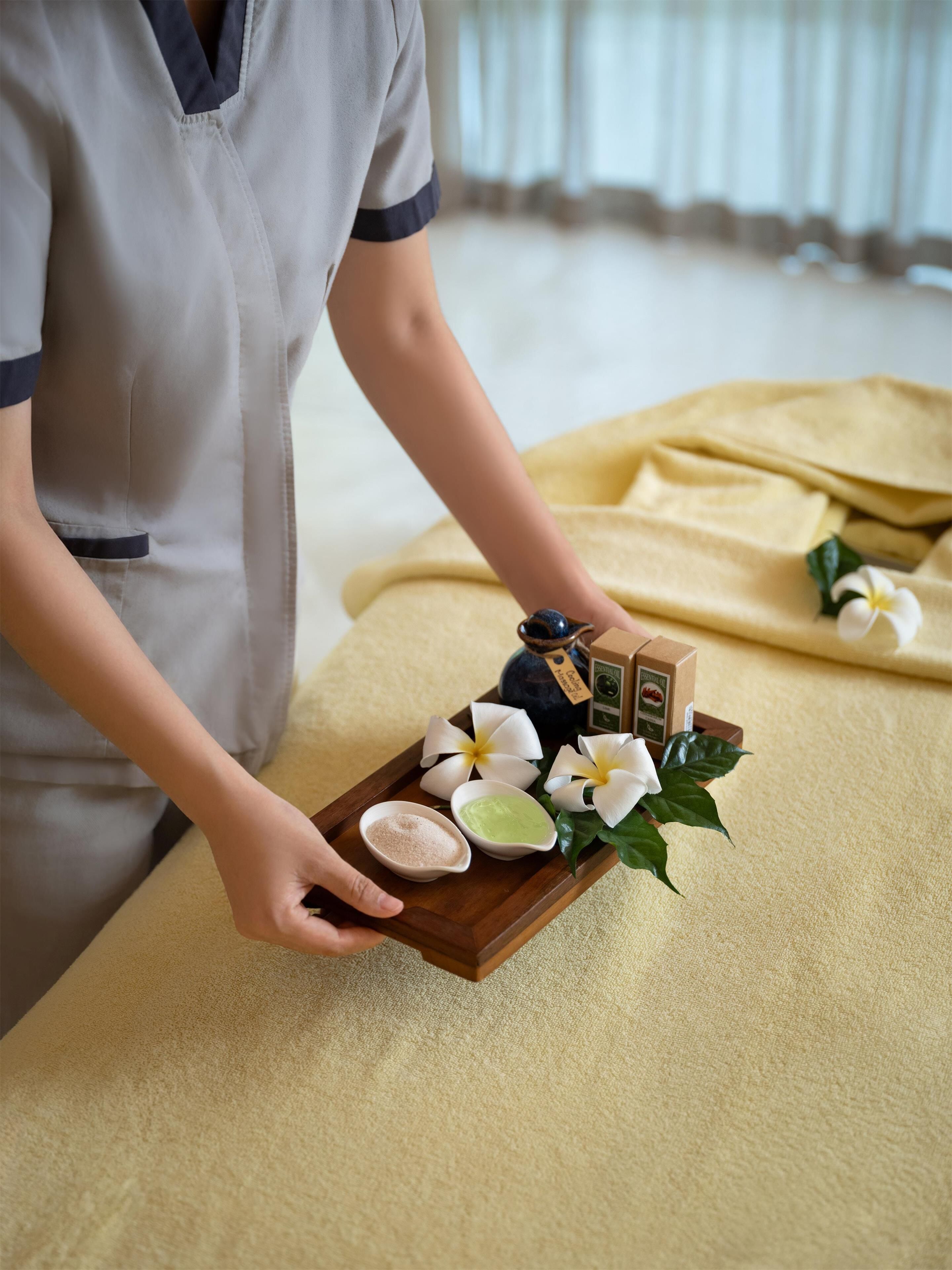 Funcionário com uniforme segurando uma bandeja com uma flor, uma tigela pequena e uma caixa.