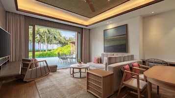 Una sala moderna con televisor, sofá, mesa de comedor y vista a un paisaje tropical.