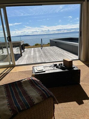 Une pièce dotée d’une grande porte-fenêtre coulissante qui donne sur une terrasse offrant une vue sur la mer.