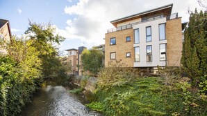 A narrow waterway flanked by buildings with modern architecture, a clear sky, and lush greenery. - The Wesley Luxury City Apartment (Oxford)