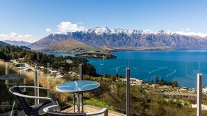 A scenic view of a lake with mountains in the background, a table and chairs in the foreground, and a small village on the opposite shore. - 9b on Von - Breath-taking Views (Queenstown)