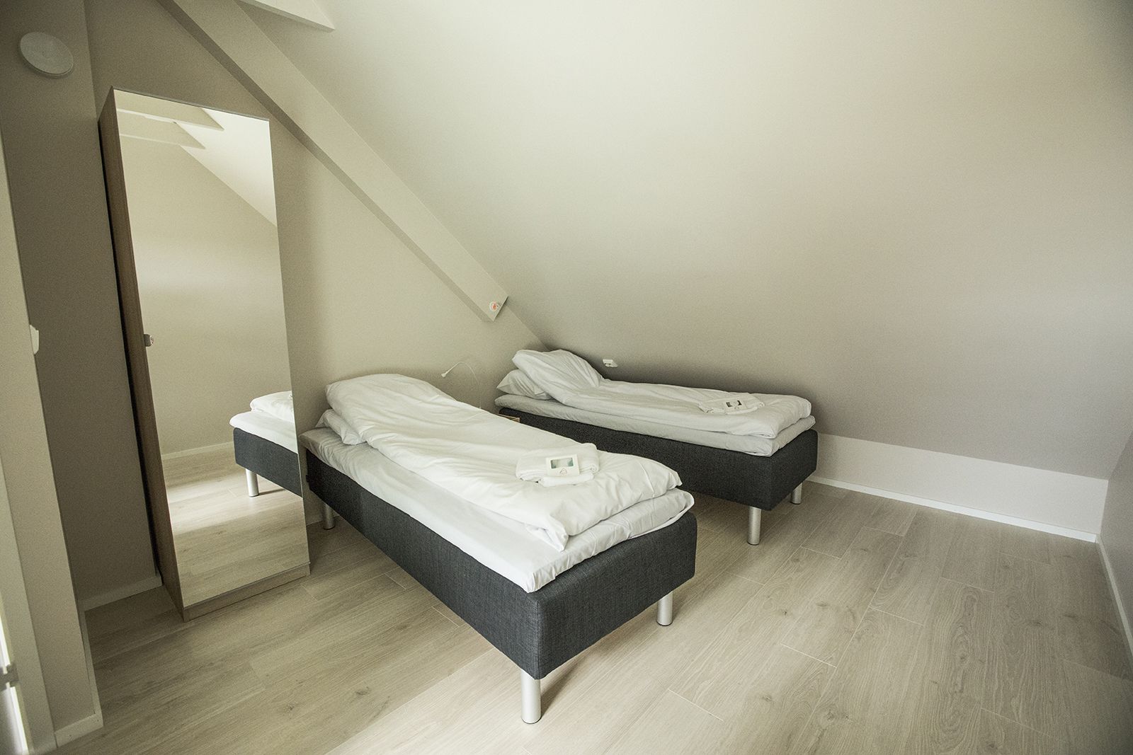 A bedroom with two single beds, a wooden floor, and a sloped ceiling.