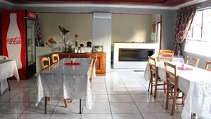 A dining area with a table and chairs, a refrigerator, a fireplace, and a Coca-Cola sign.