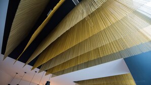 A modern interior with hanging golden fabric structures and black pendant lights. -  Room Gran Vía (Madrid)