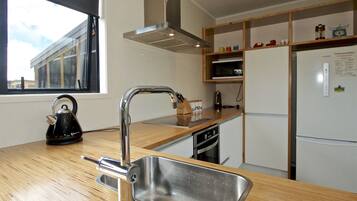 A modern kitchen with a stainless steel sink, wooden countertop, and a window providing natural light.