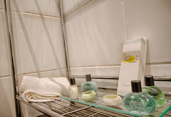A bathroom shelf with toiletries including a towel, a shaving kit, and various bottles. - Holcombe House (Llandudno)