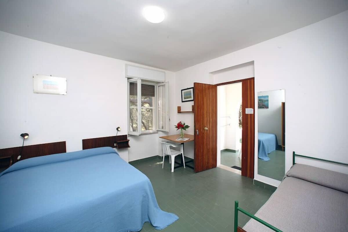 A bedroom with a bed, a desk, and a chair.