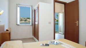 A bedroom with a bed, a window with a view of the sea, and a door leading to an outdoor area. - Residence M3 (Peschici)