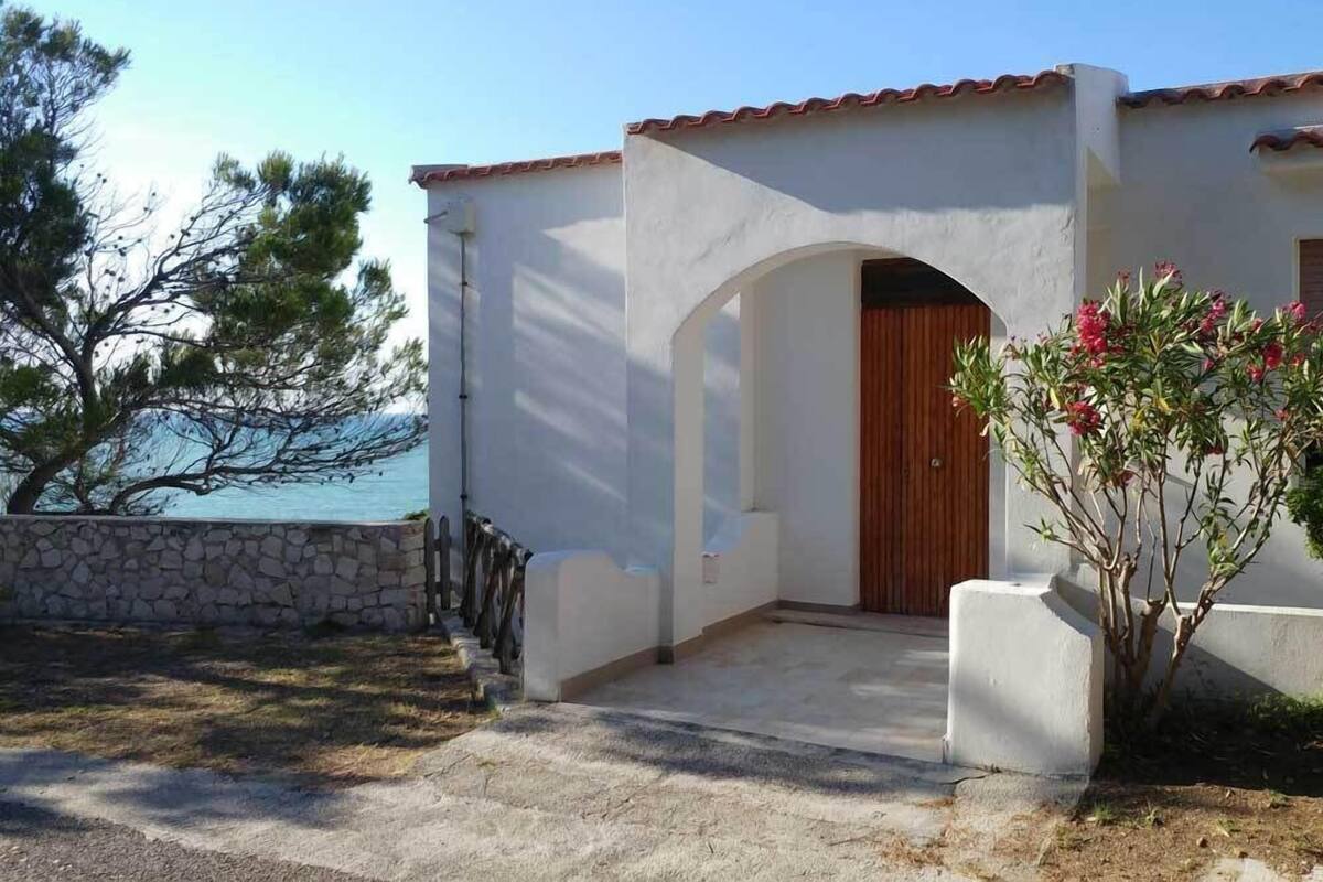 A coastal building with a stone wall, a wooden door, and a view of the sea.