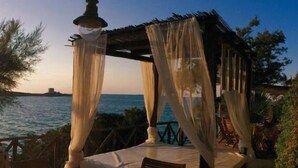 Un pabellón frente al mar con una mesa y sillas, con vista al océano.