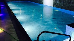 Una piscina amb una paret fosca i amb textura, i una zona al costat amb una cadira.