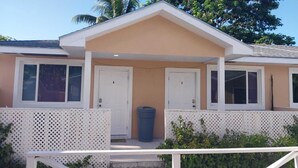 A two-story building with a beige facade, white doors, and a covered porch area. - Studio D - Queen Room (Chippingham)