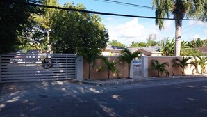 A gated property with a white fence, palm trees, and a beige wall. - Studio D - Queen Room (Chippingham)