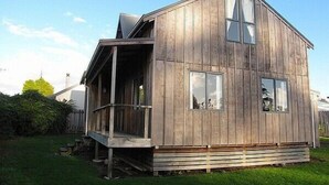 A wooden cabin with a porch, large windows, and a chimney. - Arawa Escape - Ohakune Holiday Home (Ohakune)