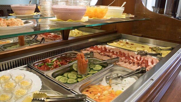 Un bufé con diversas opciones de comida, incluyendo carnes, quesos y frutas.
