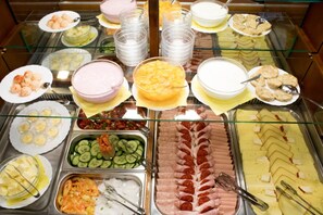 A buffet with various food items including sliced meats, cheeses, and vegetables. - Komfort Hotel Platán (Harkany)