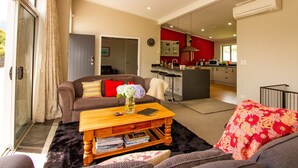 A modern living room with a sofa, coffee table, and a view into the kitchen. - 1 bedroom Restful retreat w/Spa for couples (Ohakune)