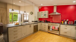 A modern kitchen with a red accent wall, stainless steel appliances, and a large island with a sink. - 1 bedroom Restful retreat w/Spa for couples (Ohakune)